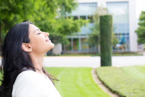 young woman in white shirt breathing in fresh crisp air after long day of work-img-blog